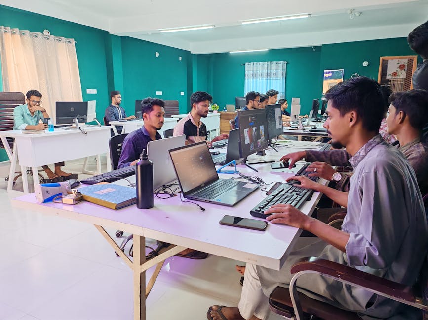 Young professionals working in a bright, modern office environment on computers, fostering collaboration and productivity.