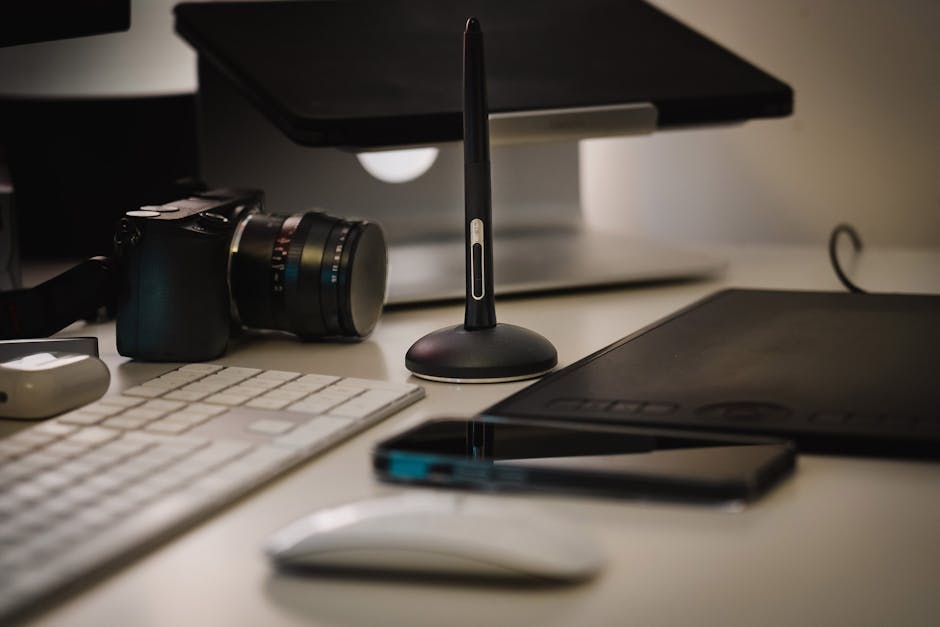 A sleek office desk featuring tech gadgets including a camera and digital drawing tablet.