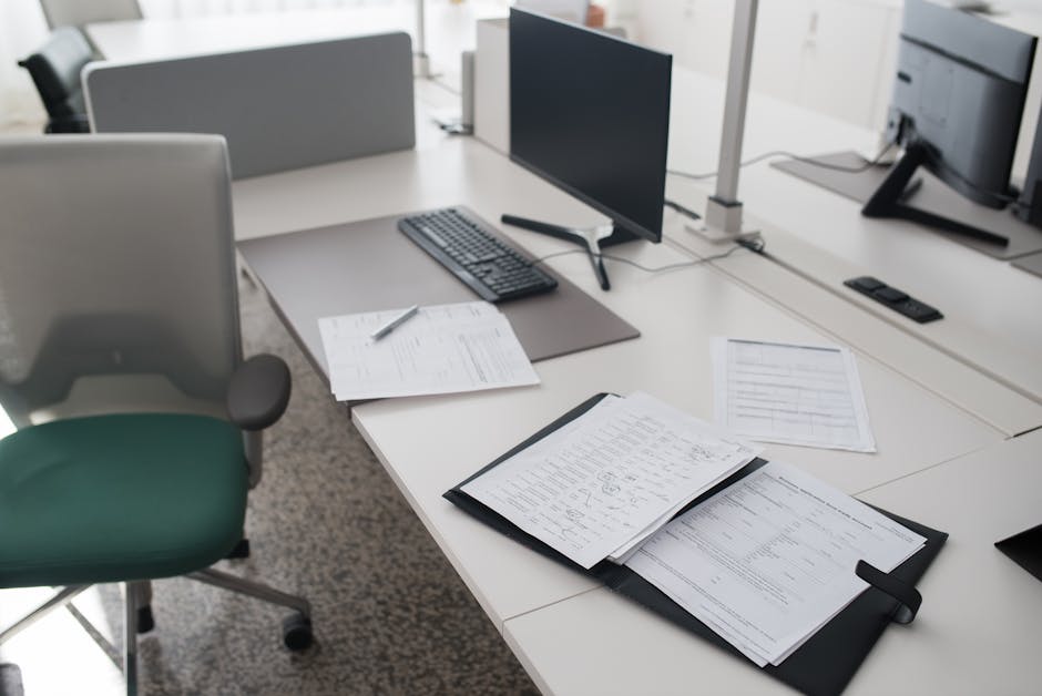 A clean and organized office desk with documents, a computer, and chair in a modern workspace.